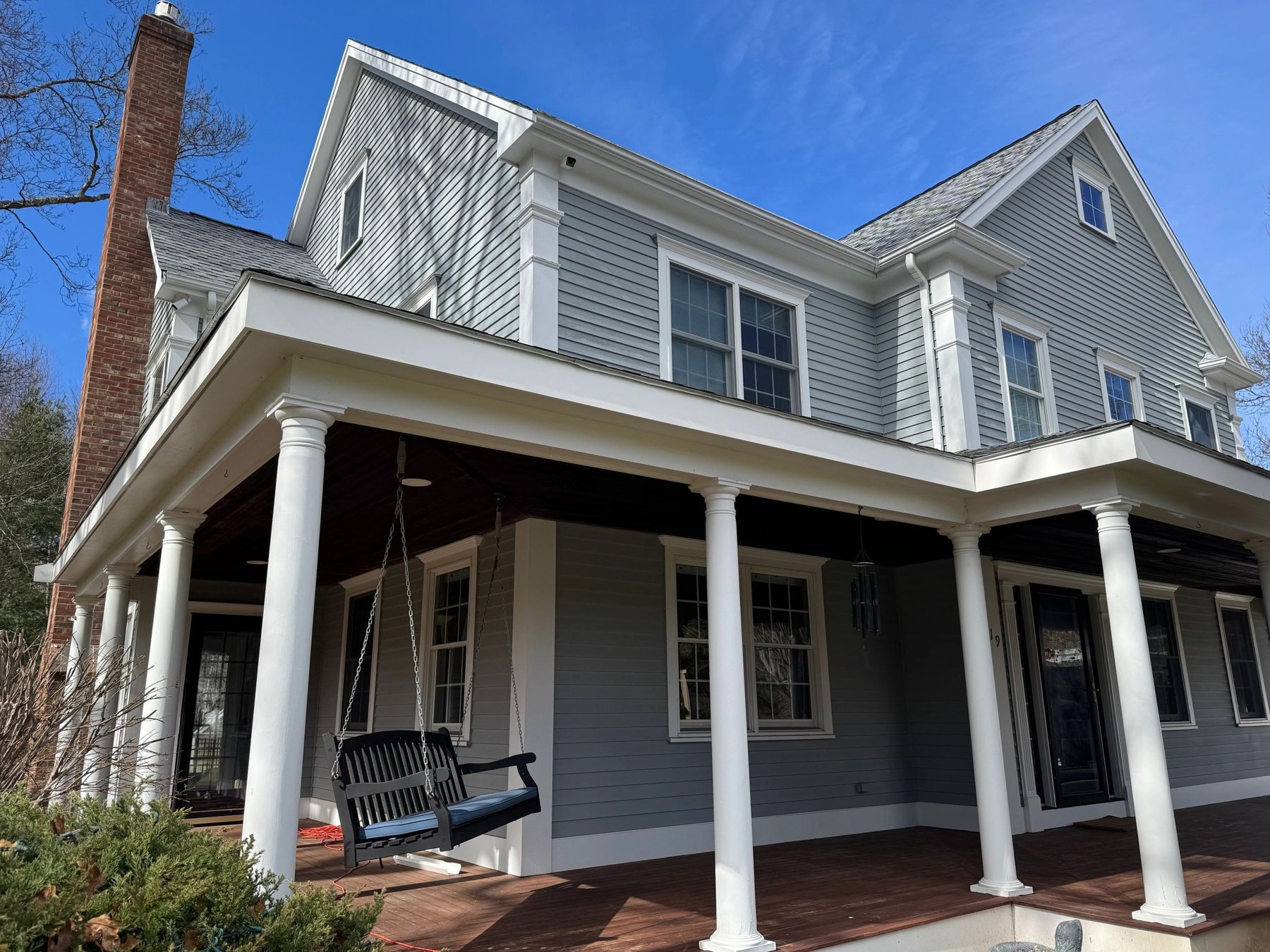 Gray home with white gutters and a wraparound porch